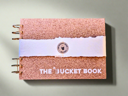 Cork-bound notebook with 'The Bucket Book' branding on a textured background